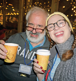 A father and daughter, both grads, pose with the cups they're drinking from